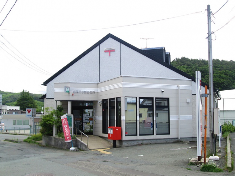 三角の屋根が特徴的な盛岡三ツ割郵便局の外観。赤い郵便ポストがあります。