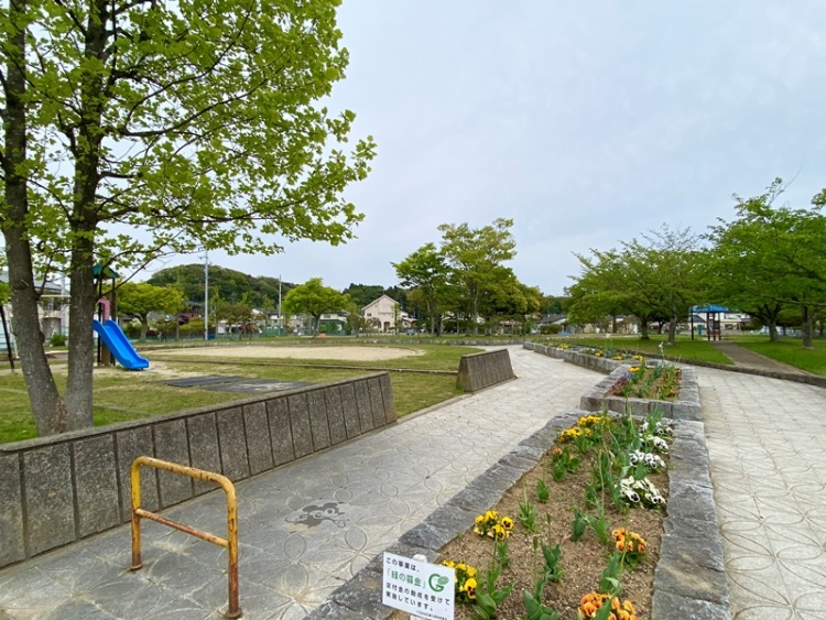 岡小名公園の外観。遊具、花壇、緑地広場が見え、散歩やジョギングに適した道もあります。