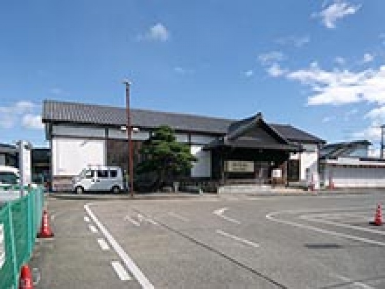 白い壁と伝統的屋根が特徴的なJR相馬駅の外観。前に駐車スペースがあります。