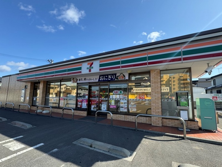 セブンイレブンの〜店の外観。駐車場とガードレールが見えます。