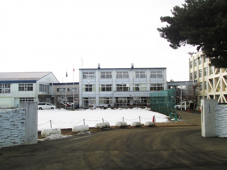 雪の積もった校庭と白い三階建ての校舎がある白銀小学校の外観です。