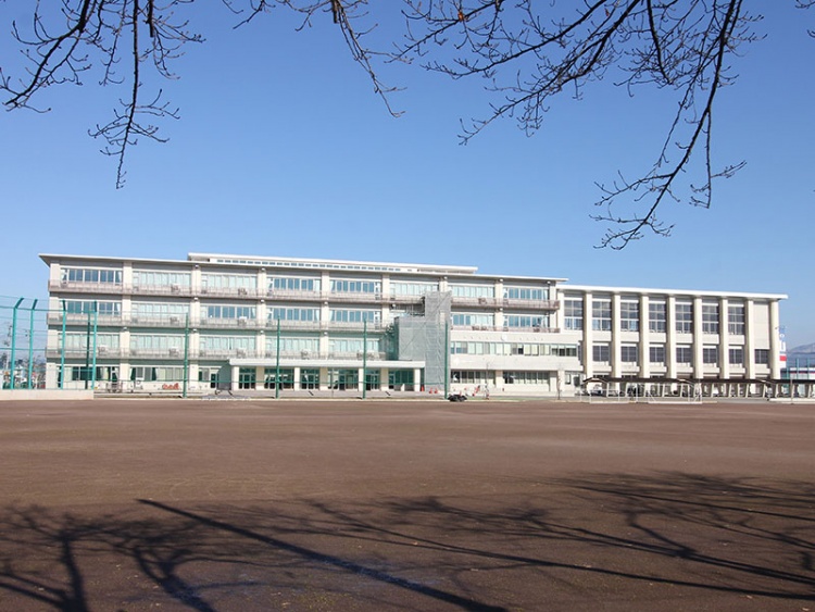 四階建ての第4中学校の校舎。校舎の前に広いグラウンドが広がっています。