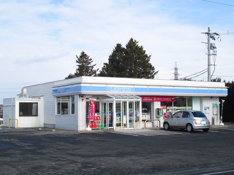 ローソンの店舗外観です。駐車場に車が1台停まっています。後ろには木々と電柱が見えています。
