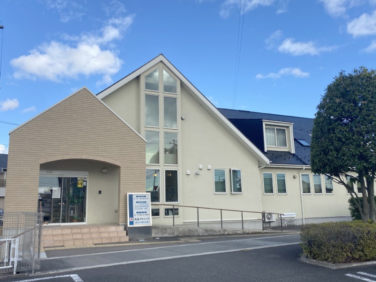 クリーム色の二階建て建物の外観。左側に入り口があり、右側に窓が並んでいます。