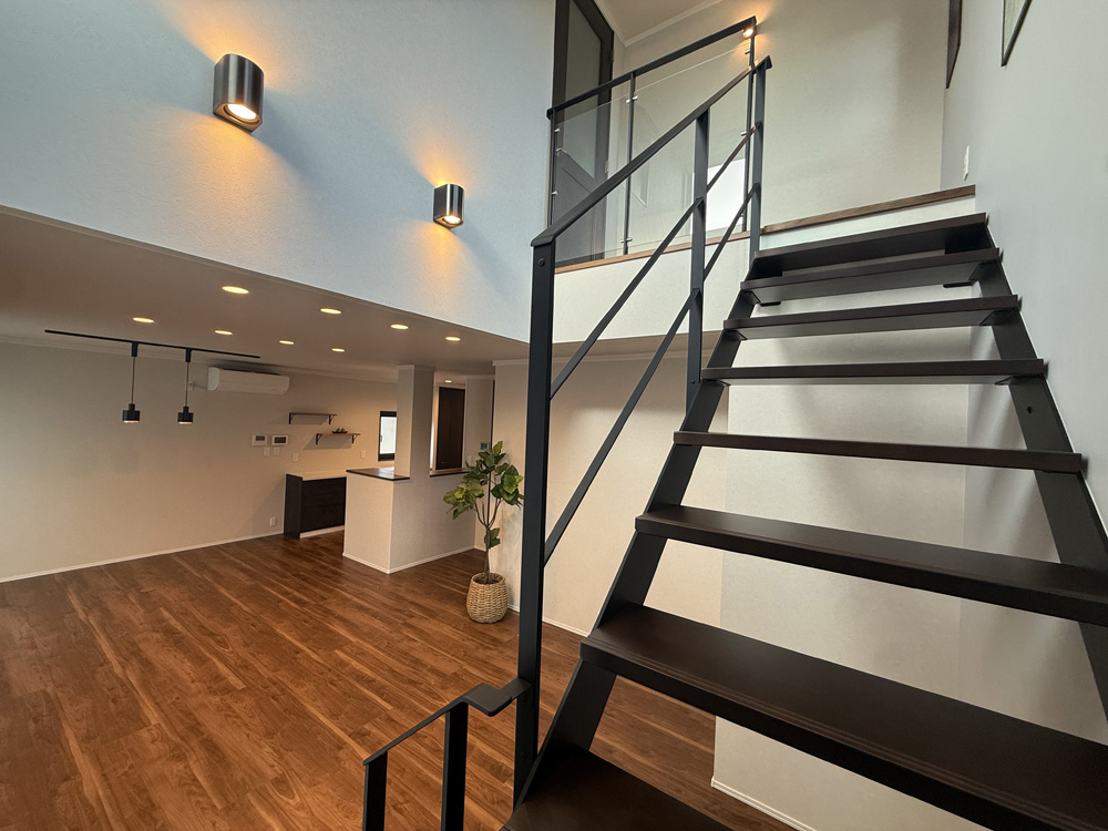 上へと続く黒い階段が印象的な室内。天井が高く、ぬくもりある床とやさしい灯りが心落ち着く空間をつくっています。