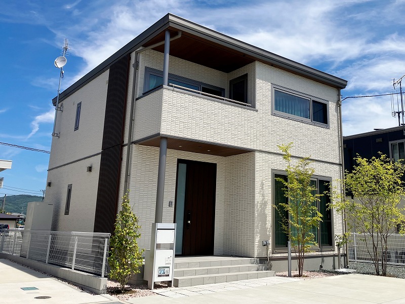 白の外壁の二階建て住宅のC棟外観。玄関横に植栽が植えられていて、郵便受けが見えます。