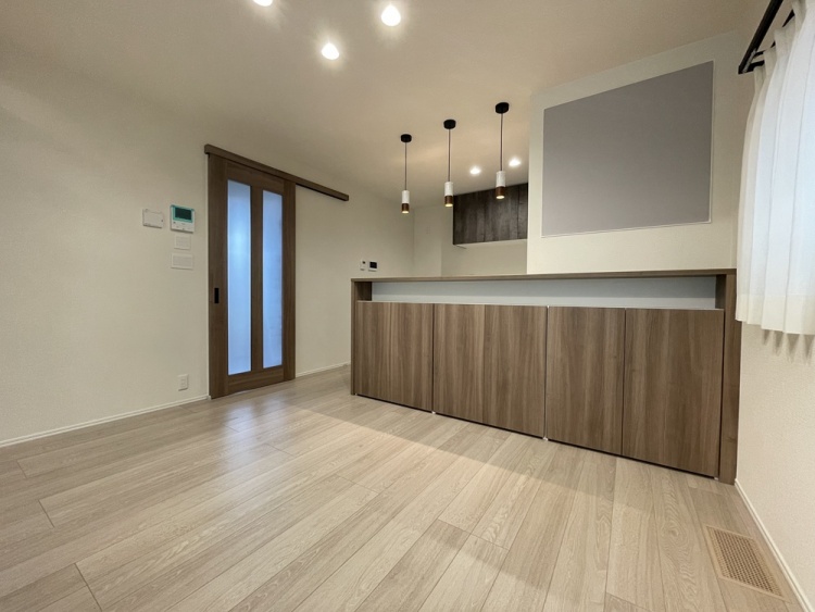 木目調のカウンター収納とペンダントライトが印象的なダイニング空間です。明るい床材と白い壁で、すっきりとした雰囲気にまとめられています。