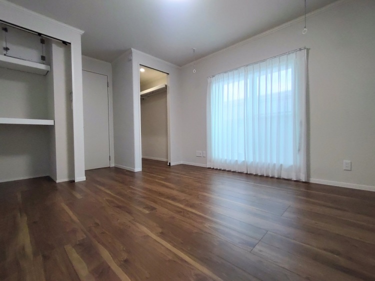 窓から柔らかな光が差し込むコンパクトな部屋。ナチュラルな木目の床と白い壁が穏やかな雰囲気を演出している。奥には収納付きのクローゼットが備えられている。