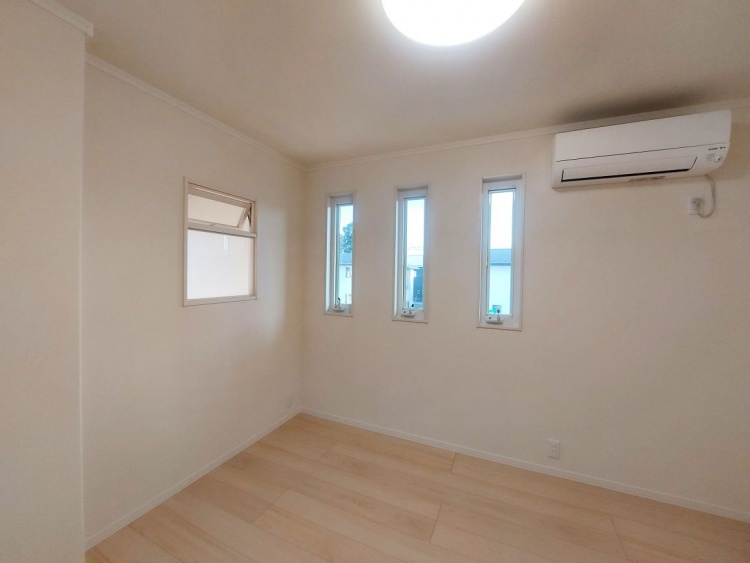 縦に並んだ三つの細長い窓からやさしい光が入り、明るい木目の床が穏やかに広がる静かな部屋です。