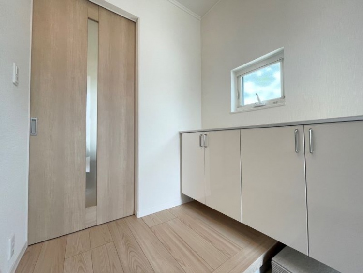 明るい木目調のフローリングと建具が調和した玄関ホール。収納力のあるシューズボックスと小窓からの自然光で、清潔感と開放感のある空間に仕上がっています。