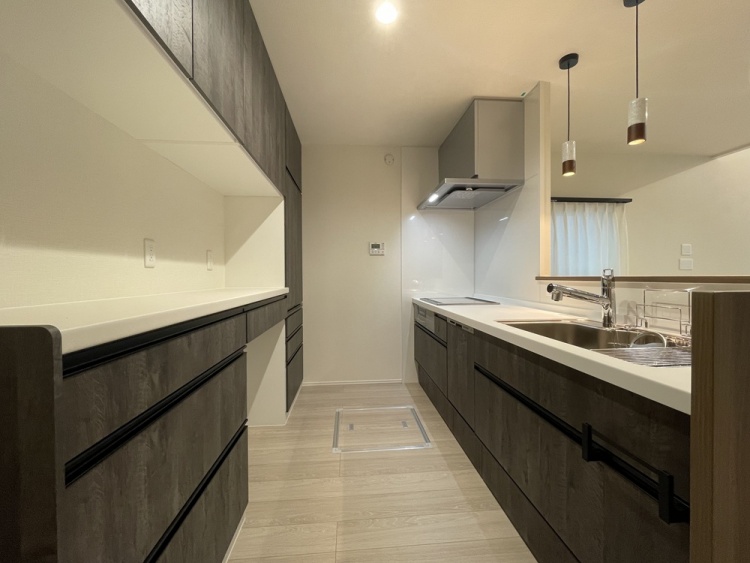 対面式のシステムキッチンです。シンク、IHコンロ、レンジフード、食洗機、カップボードを備え、収納力のある設計になっています。