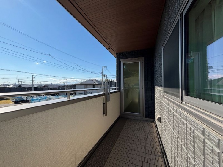 空の青さが広がる景色を見渡せるバルコニーで、白い壁と手すりが爽やかに映えています。