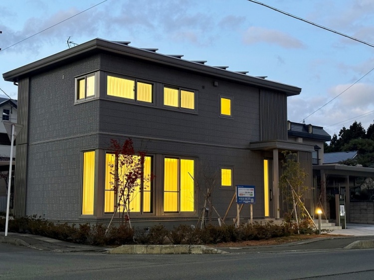 グレーの外壁の二階建て住宅外観。前に植栽があります。