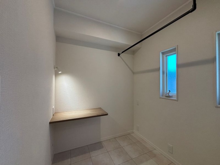 壁に設置された机と、窓、ライト、吊り下げ用のバーが設置された家事室。