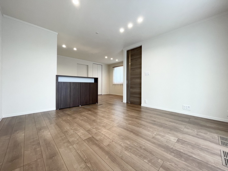 落ち着いた木目調の引き戸と、機能的な腰高の収納カウンターを備えた、広々とした明るいリビングダイニングです。