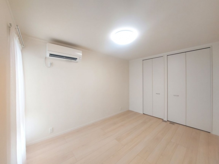 エアコンが設置された部屋に、扉の開いた広めのクローゼットが並び、明るい木の床が優しく広がっています。