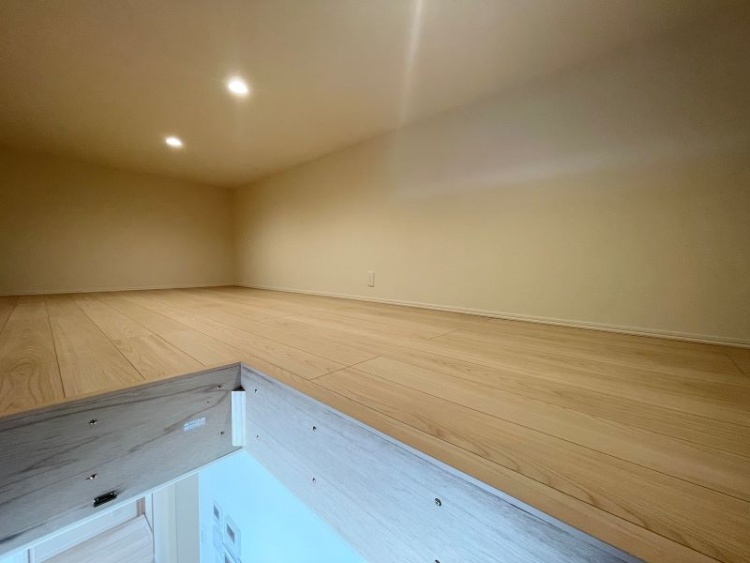 天井が低めの小さな空間に木の床が広がり、優しい灯りが壁を照らす、静かな屋根裏部屋のような空間です。