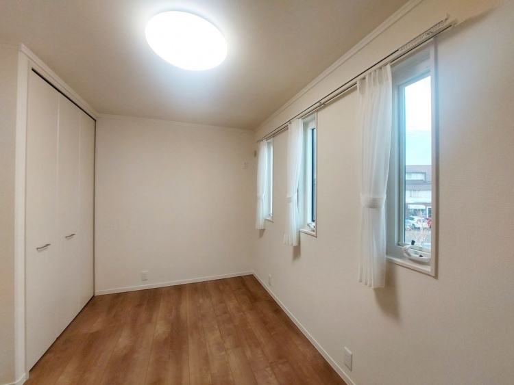 三つの細長い窓から光が入り、白い壁と木目の床が心地よい落ち着きを感じさせる部屋です。