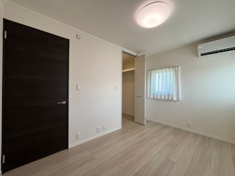 白を基調とした寝室。窓が2つ、エアコン、ウォークインクローゼットが設置されています。