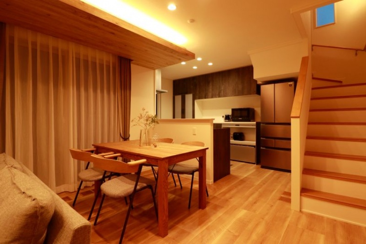 温かみのある照明に包まれたダイニング・キッチン空間。木目調の天井と床が統一感を生み、ナチュラルで落ち着いた雰囲気を演出しています。