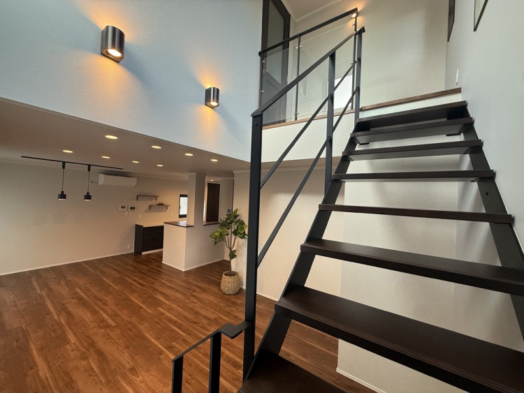 上へと続く黒い階段が印象的な室内。天井が高く、ぬくもりある床とやさしい灯りが心落ち着く空間をつくっています。