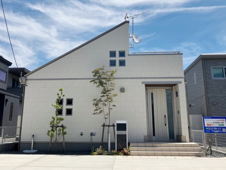 白の外壁の２階建て住宅のD棟外観。植栽が植えられていて、手前には駐車スペースが見えます。