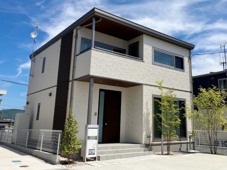 白の外壁の二階建て住宅のC棟外観。玄関横に植栽が植えられていて、郵便受けが見えます。