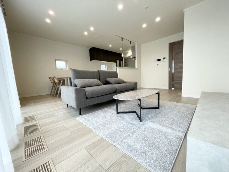 グレーのソファと大理石調のローテーブルを配置した、モダンで開放感のある広々としたLDKです。