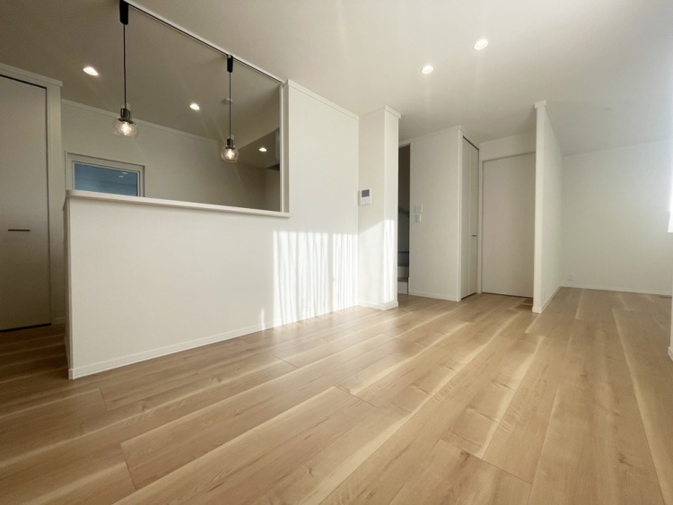 ペンダントライトがアクセントの対面式キッチンと、明るいフローリングが広がる開放的なLDKです。