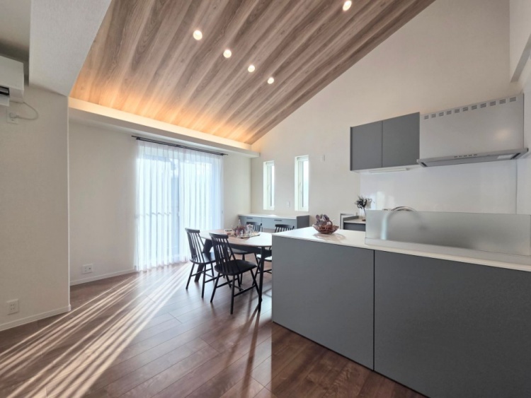 開放感あふれるリビング・ダイニング・キッチン空間。天井が高く、木目の天井材が温もりを与えています。