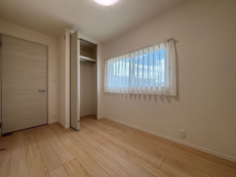 白を基調とした寝室。左側に収納とドア、右側に窓があります。