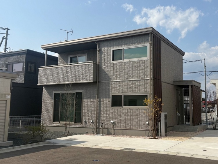 グレーを基調とした2階建て住宅のB棟外観。玄関周りに植栽が植えられています。