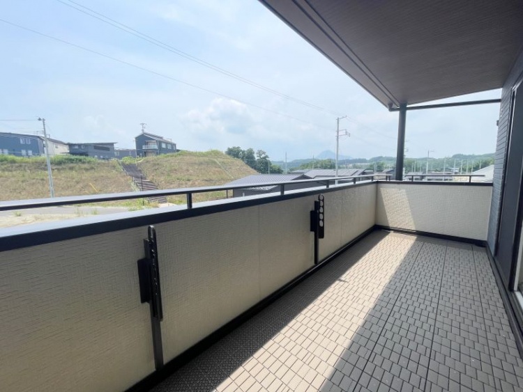 屋根付きのバルコニー。洗濯物を干す金具が設置されており、床はタイル張りです。