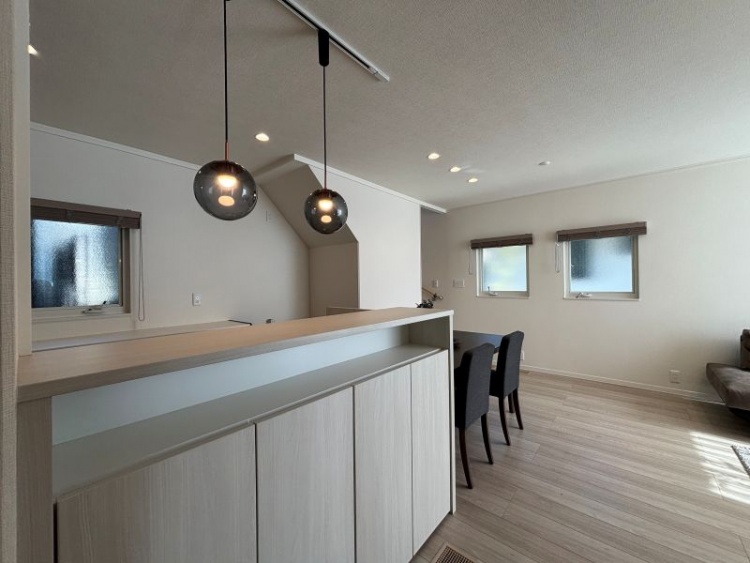 白を基調としたダイニングルーム。フロート収納とペンダイトライト、奥には窓が2つ設置されています。