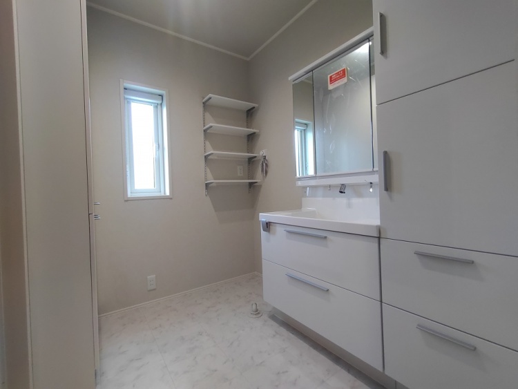 コンパクトながら機能的なトイレ空間。白を基調とした内装に、小窓からの自然光が心地よく差し込む。手洗い器や収納棚、手すりが備わり、使い勝手の良い設計になっている。