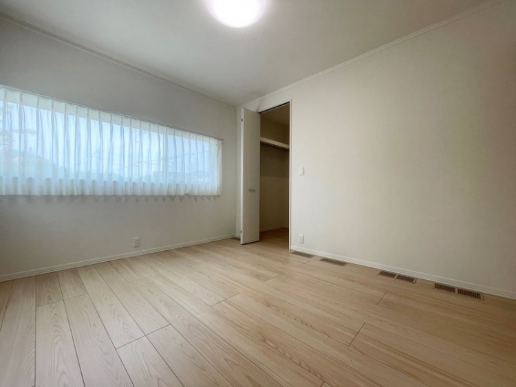 白い壁とナチュラルな木目調フローリングのシンプルな部屋。大きな窓から柔らかな自然光が入り、明るく落ち着いた雰囲気です。