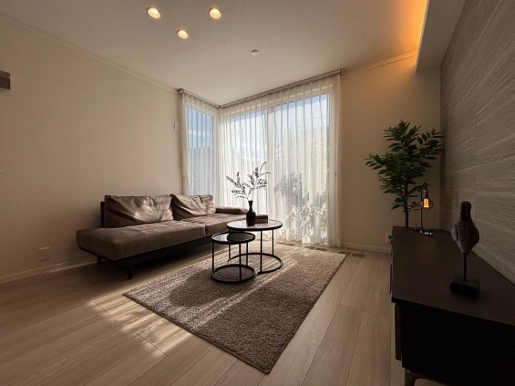 グレーのソファと丸いローテーブルがあるリビングルーム。外に出られる大きな窓があります。