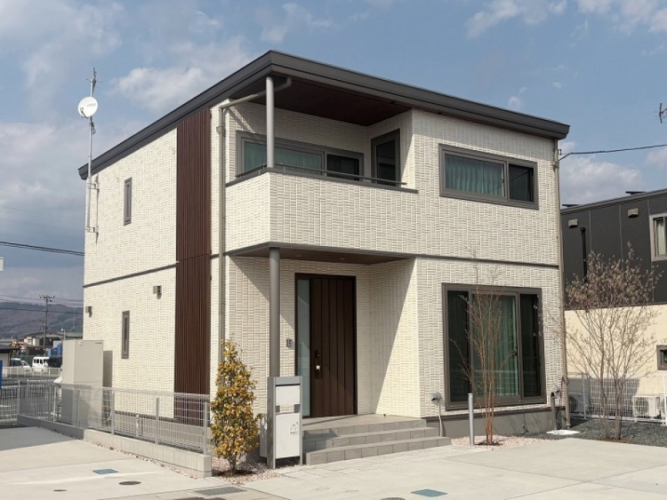 白の外壁の二階建て住宅のC棟外観。玄関横に植栽が植えられていて、郵便受けが見えます。