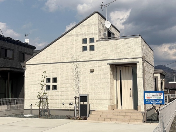 白の外壁の２階建て住宅のD棟外観。植栽が植えられていて、手前には駐車スペースが見えます。