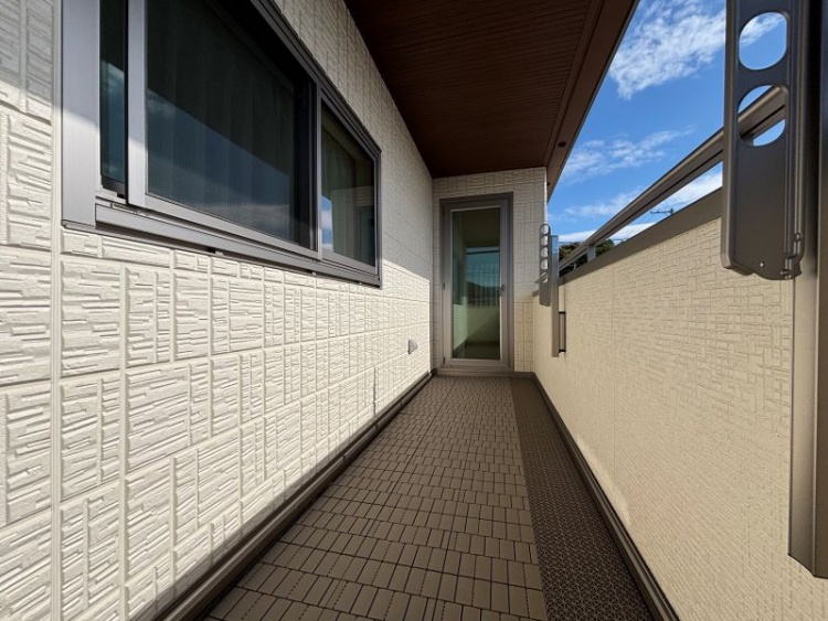 白い壁とタイル床のあるバルコニー。物干し金具と窓が見えます。