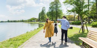 東北6県の不動産情報トップページへのリンク画像です。湖のほとりを歩く家族の後ろ姿。両親が小さな子どもを両手で持ち上げて遊んでいる様子で、青空と緑豊かな公園が広がっています。