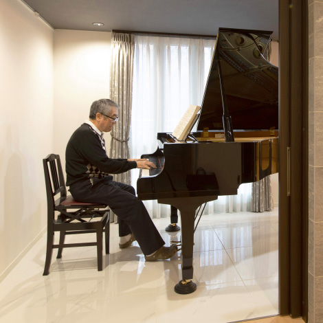 piano spaceイメージ画像。男性がピアノを弾いている様子。部屋には大きな黒いグランドピアノがあり、音楽を楽しんでいるような雰囲気です。