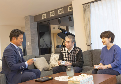 イメージ画像。リビングルームで3人がソファに座り、くつろぎながらお茶を楽しんでいます。背景にはピアノが置かれ、落ち着いた雰囲気の空間です。