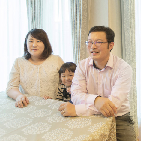 Reliefのイメージ画像。テーブルに座る家族の写真です。母親と父親が並んで座り、二人の間から女の子が顔を覗かせて笑っています。背後から差し込む光が、家族の温かな雰囲気を一層引き立てています。