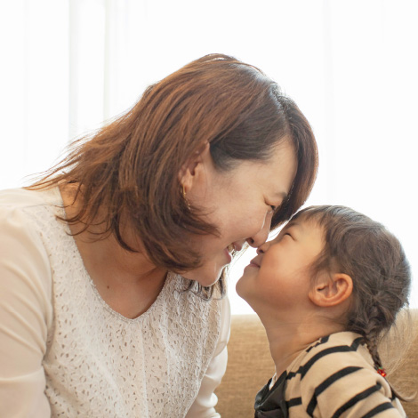 Commitmentのイメージ画像。母親と娘が額を寄せ合って笑顔を交わしています。お互いの鼻が触れ合い、親子の温かい絆が感じられる微笑ましい瞬間です。背景には柔らかな光が差し込んでいます。