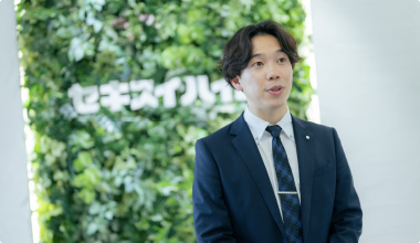 Topスライダー画像07スーツ姿の男性が、緑の壁を背景にして話している様子。「セキスイハイム」のロゴが後ろに見えます。